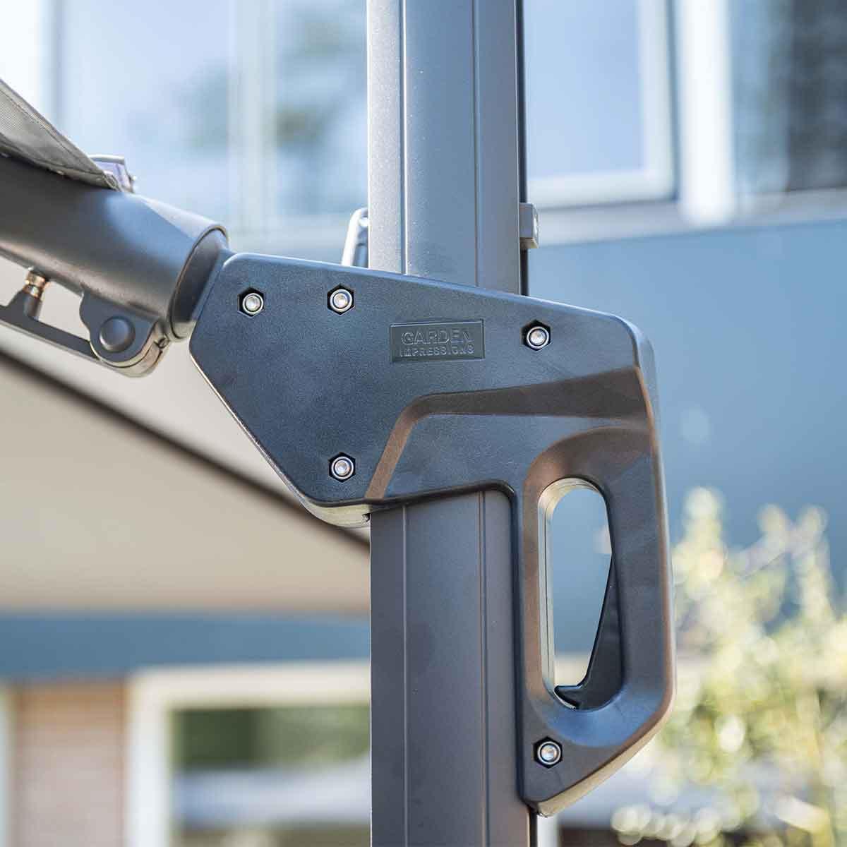 Close-up van een zwarte handgreep met de woorden "GARDEN IMPRESSIONS" op een grijze metalen paal.