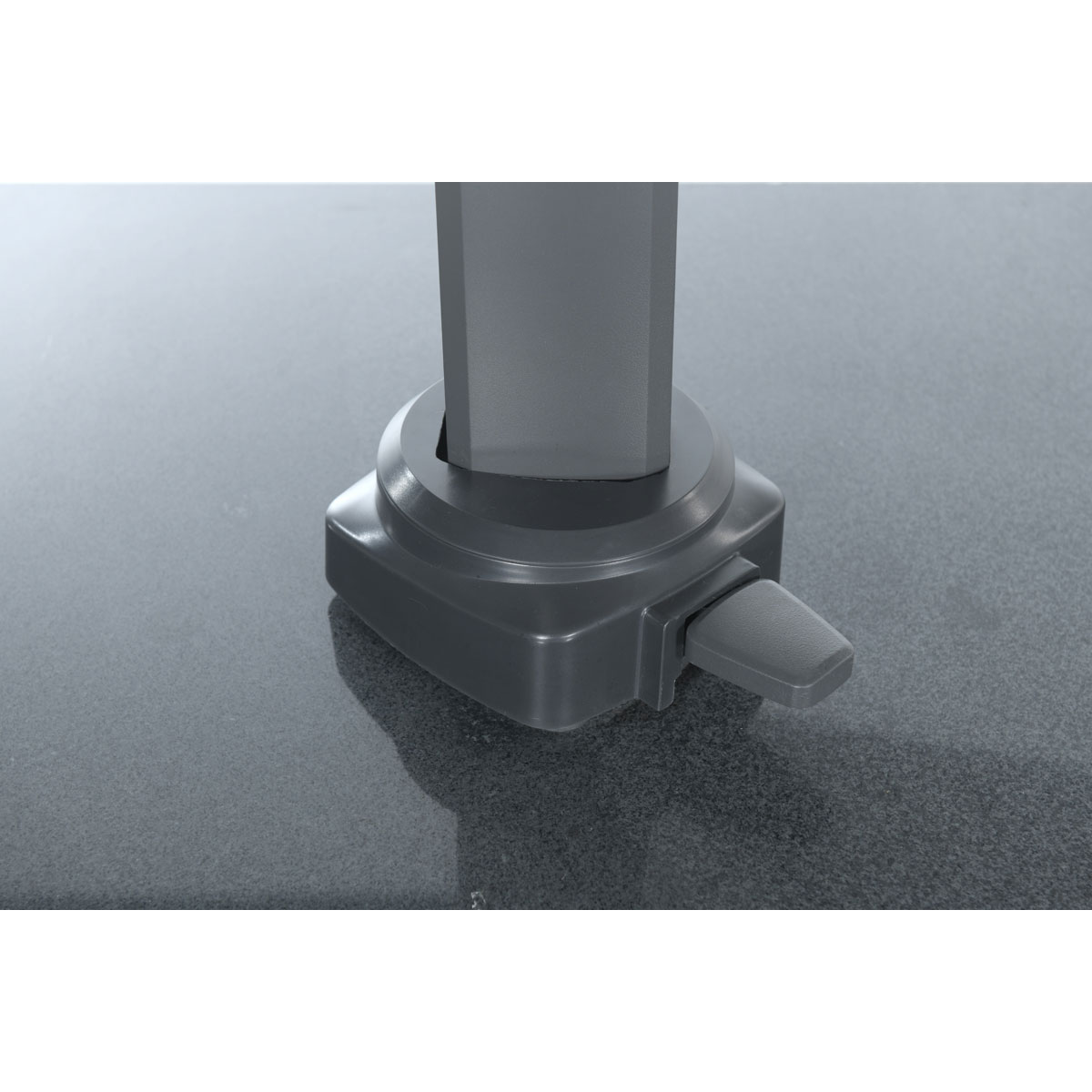 Close-up of umbrella base with lever, on a textured surface.