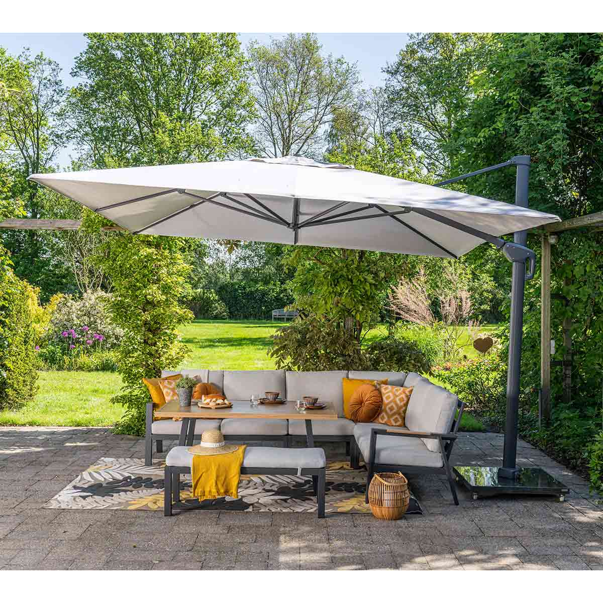 Patio met een grote witte parasol boven een tafel met eten en kussens.