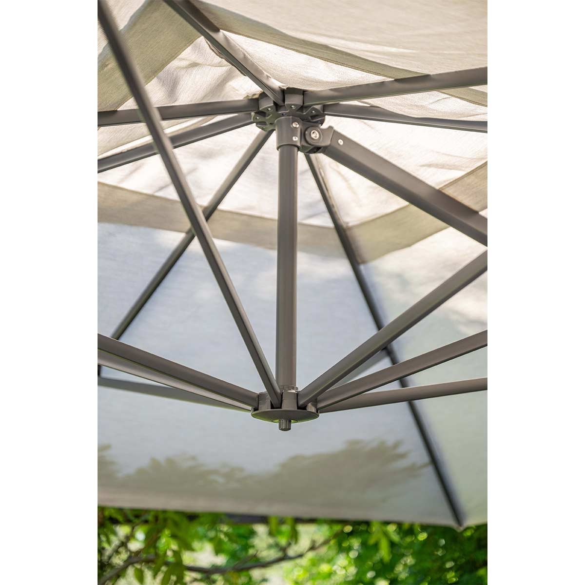 Close-up van het frame van een witte parasol, met metalen steunen en stof, van bovenaf verlicht.