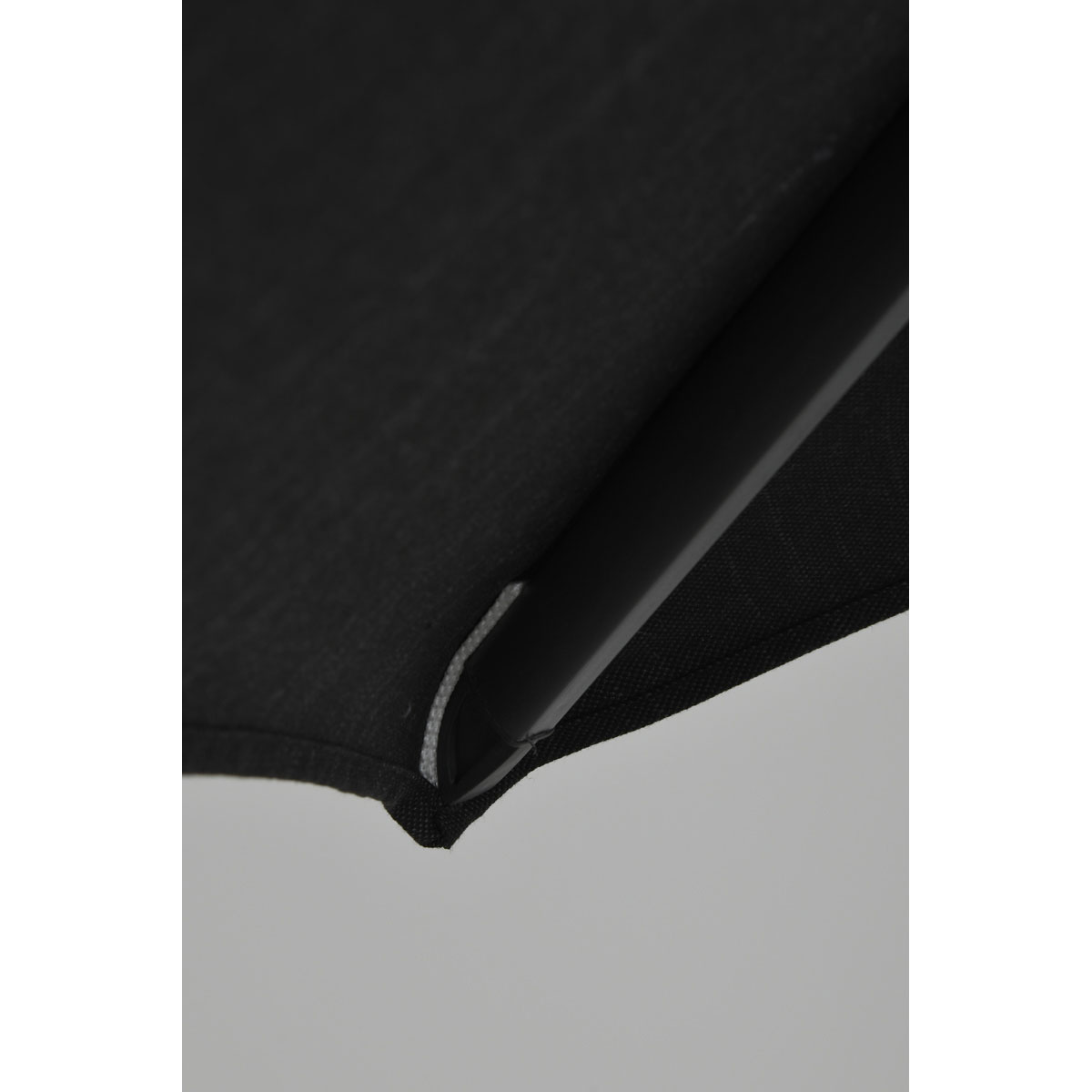 Close-up of black umbrella fabric edge, showing the stitching and a metal support.