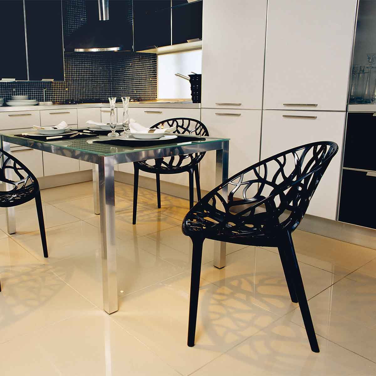Modern kitchen with black chairs, glass table, and cabinets.