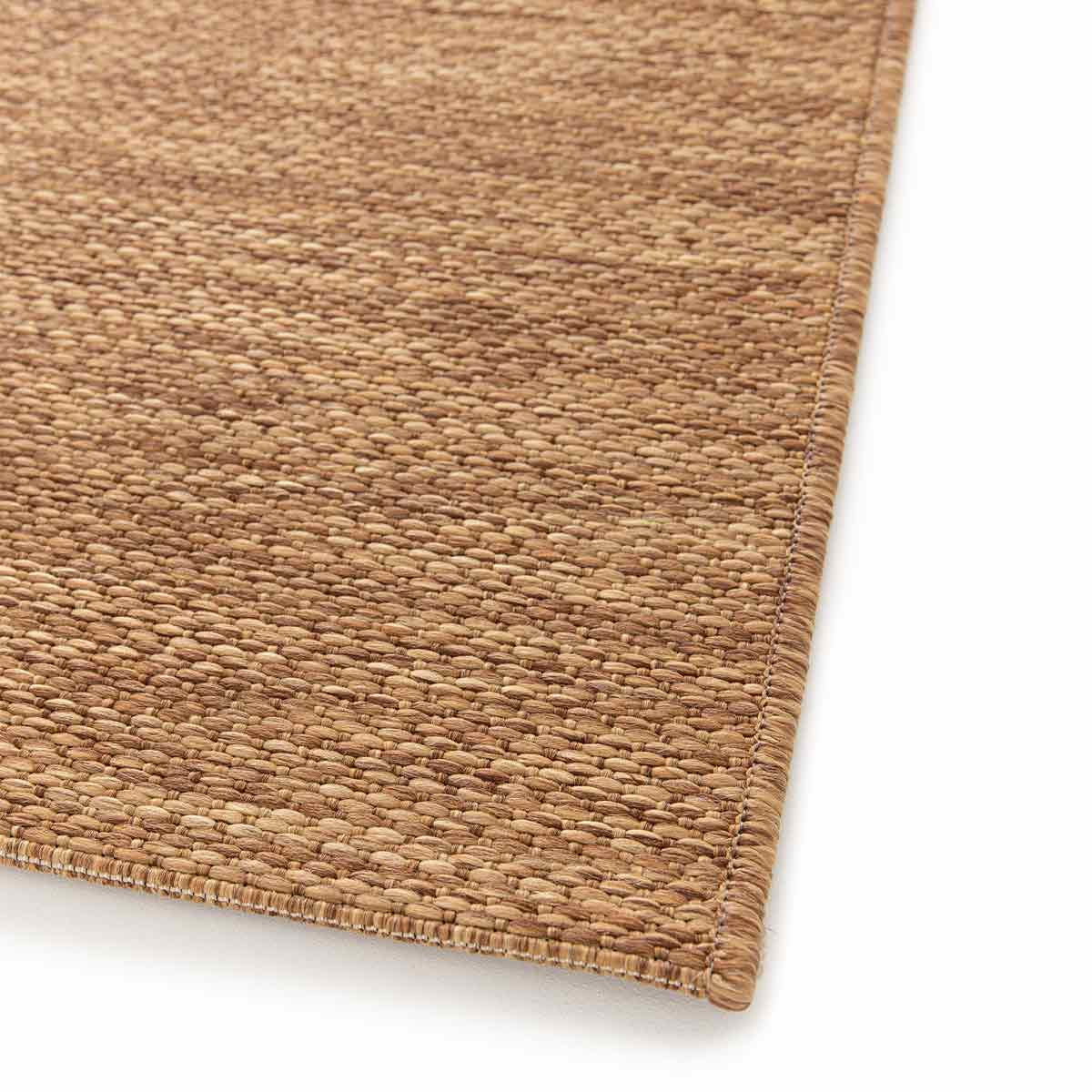 Close-up van een geweven bruin tapijt. De textuur is zichtbaar. Witte achtergrond.