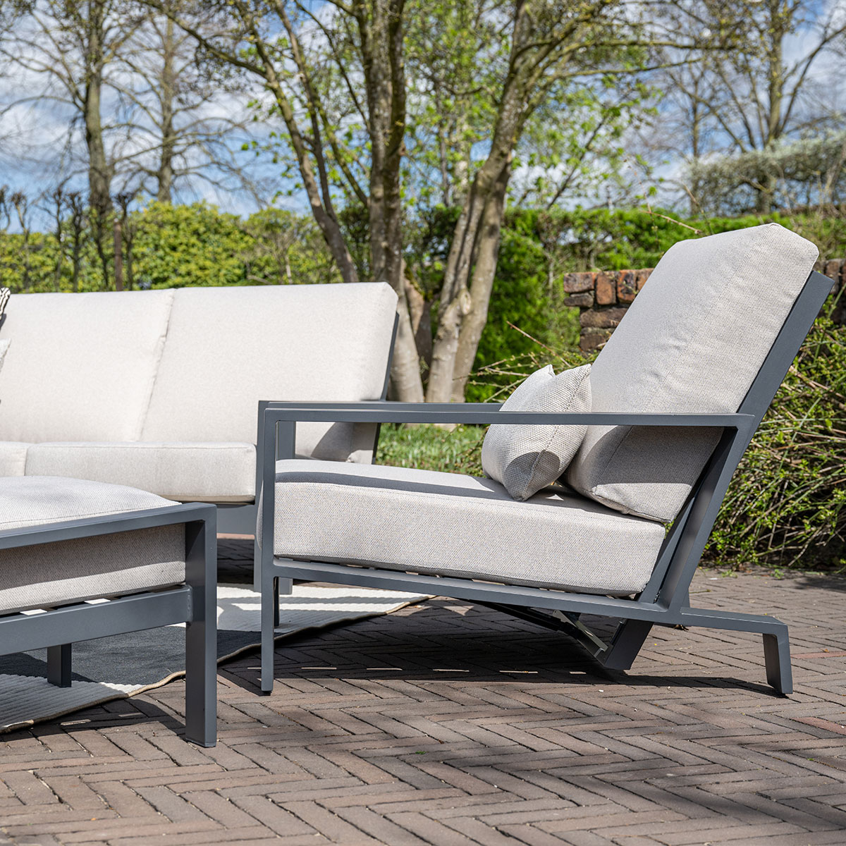 Outdoor seating area with grey chairs, cushions, and brick patio.