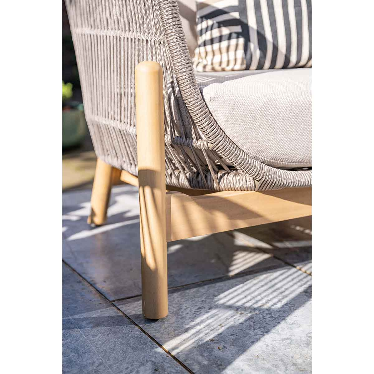Chair with woven design. Wooden legs, gray cushion, and pillow.
