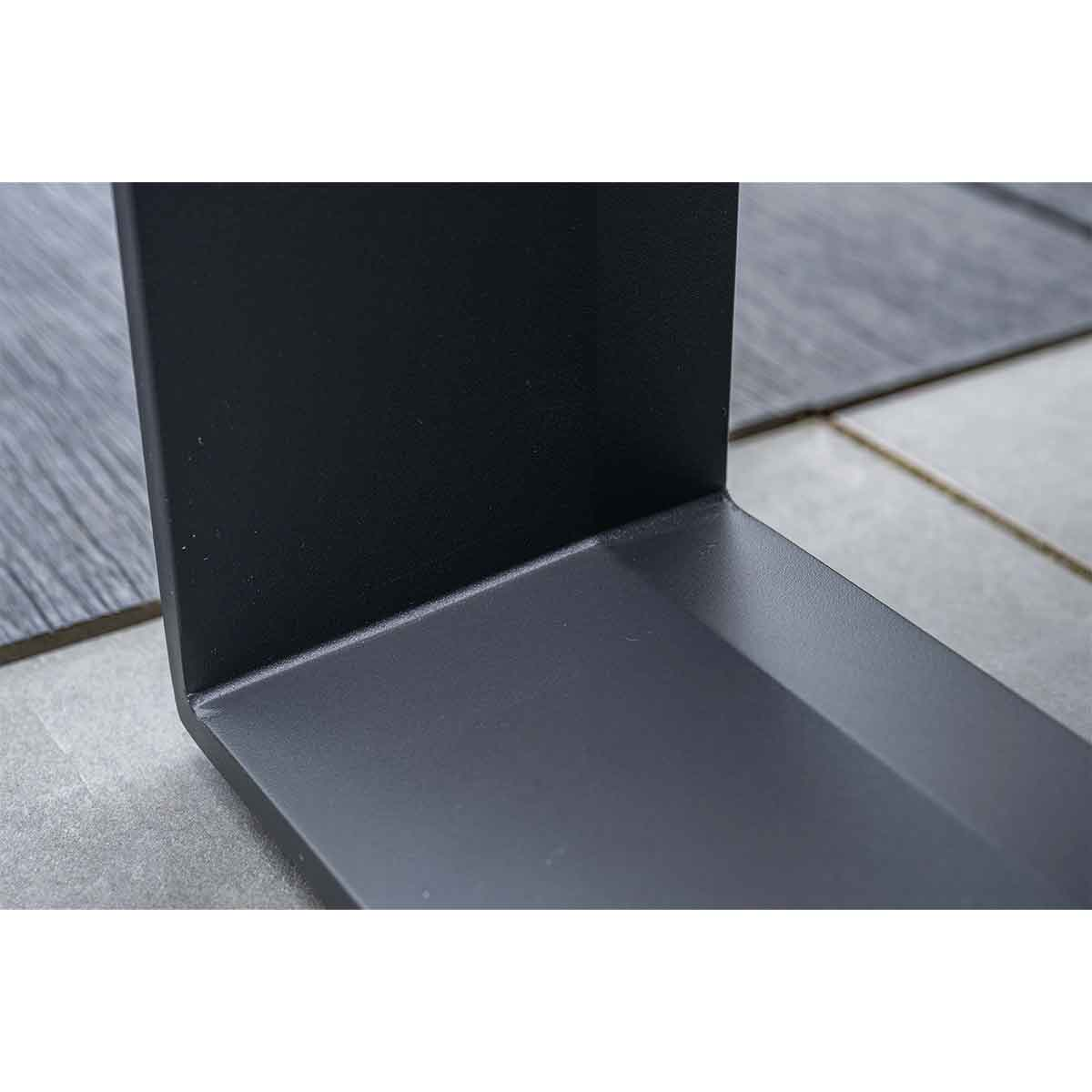 Close-up of a black, L-shaped metal bracket, placed on a surface of gray and beige tiles.