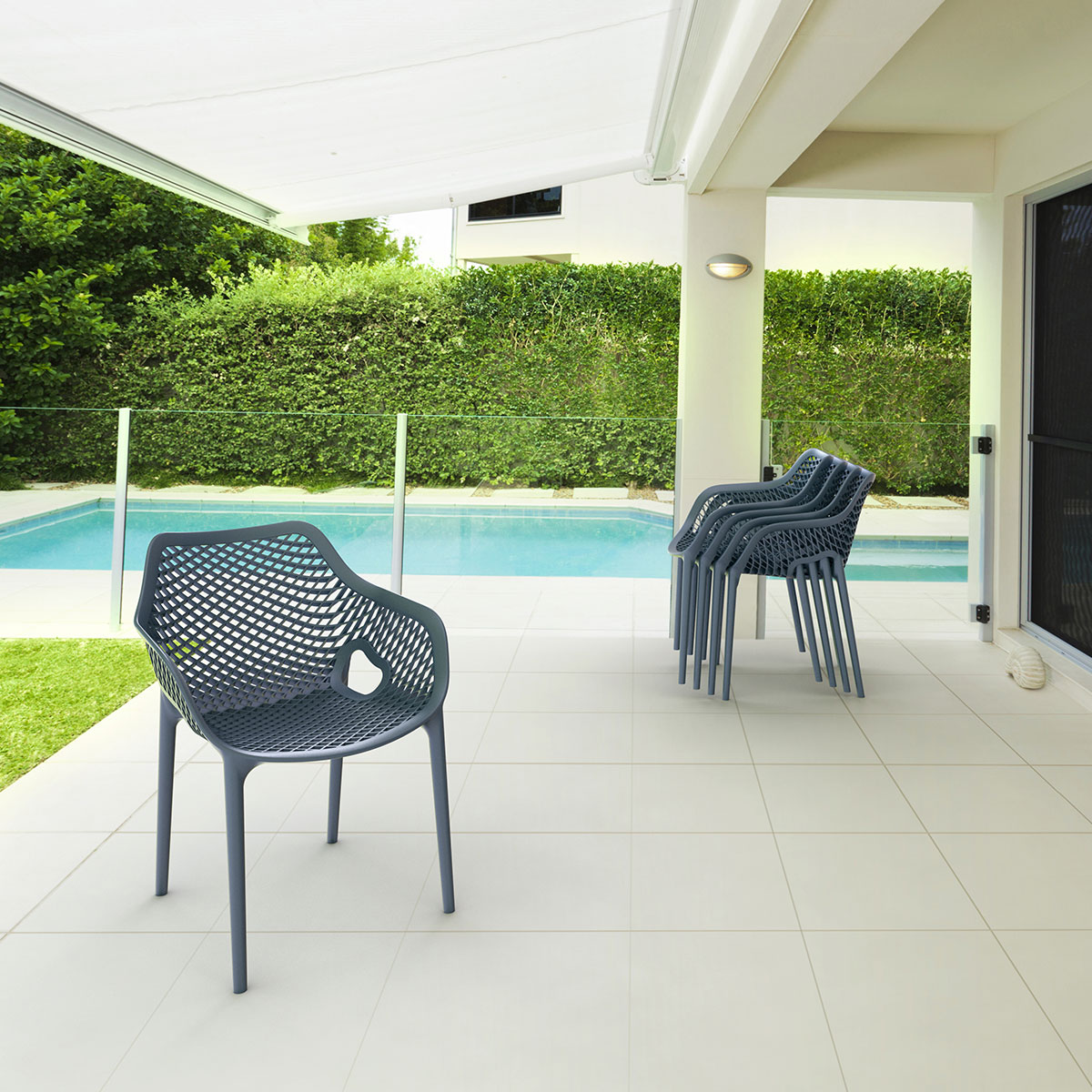 Patio avec piscine, chaises et une haie verte.