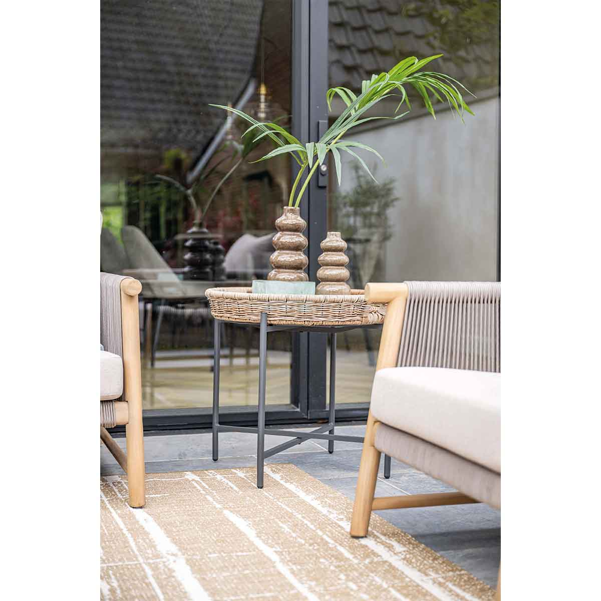 Table basse en osier avec éléments de décoration. Porte vitrée en arrière-plan.