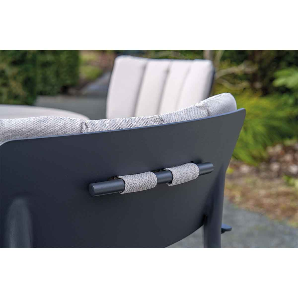 Gros plan sur le dossier d'une chaise avec coussins gris et cadre gris foncé.