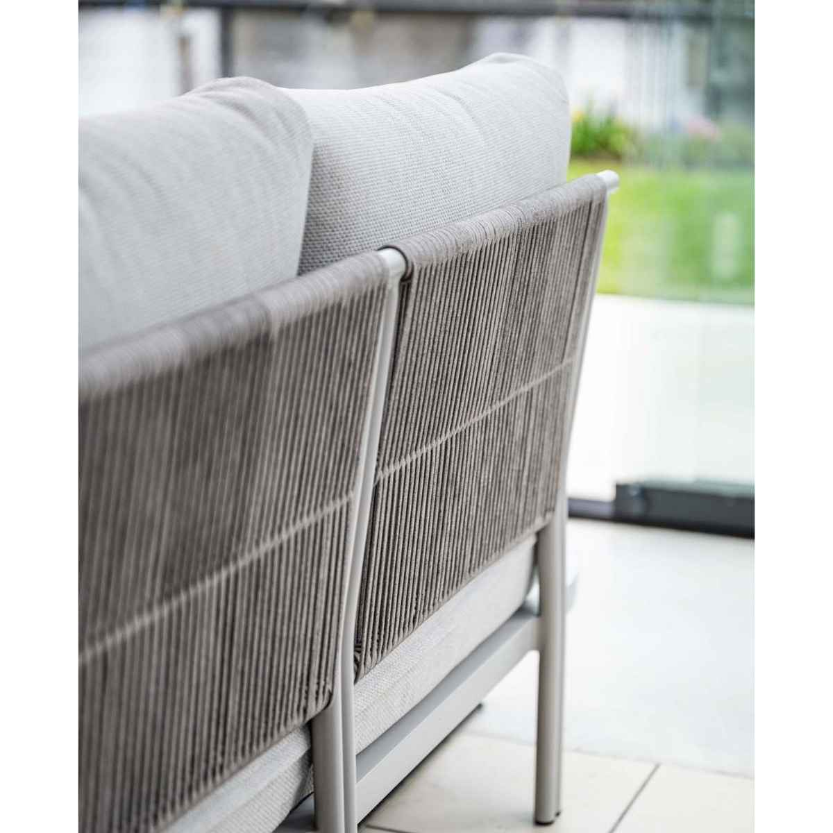 Close-up of a grey rope-backed sofa with light cushions.