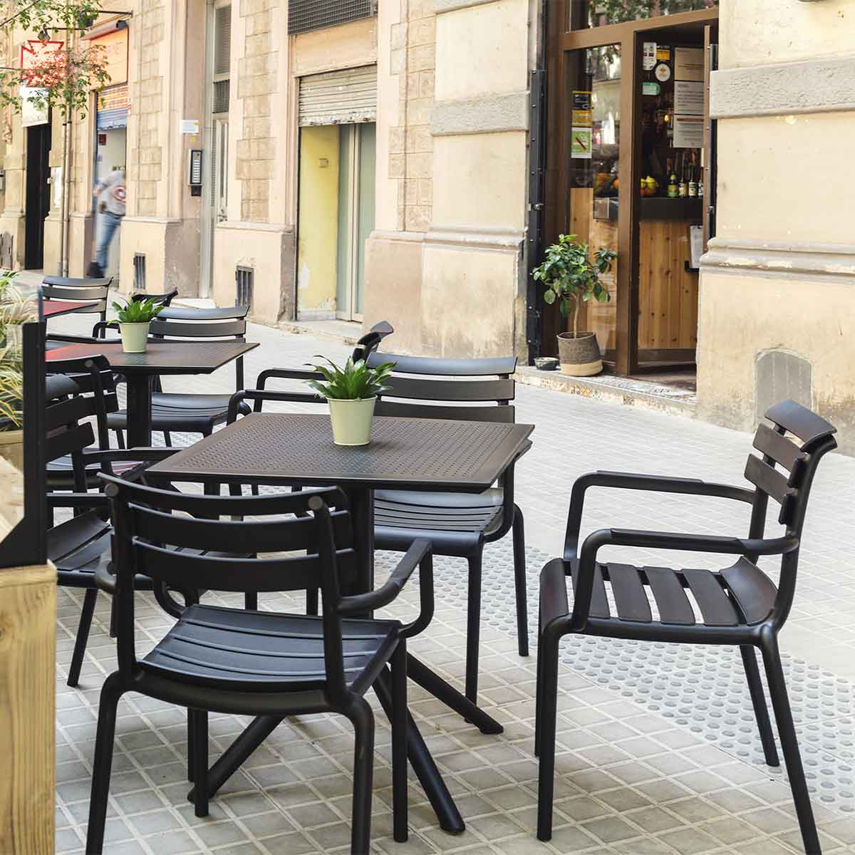 Buitentafels en -stoelen van een café op een betegelde straat.