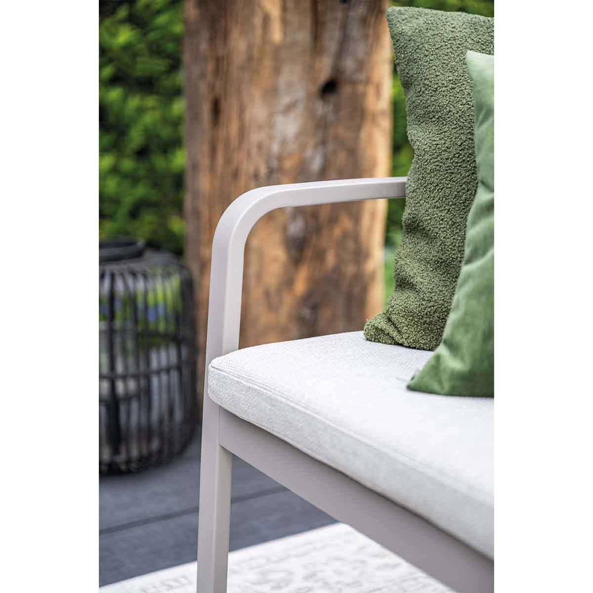 Gros plan sur des coussins verts sur un banc. Fond de jardin.