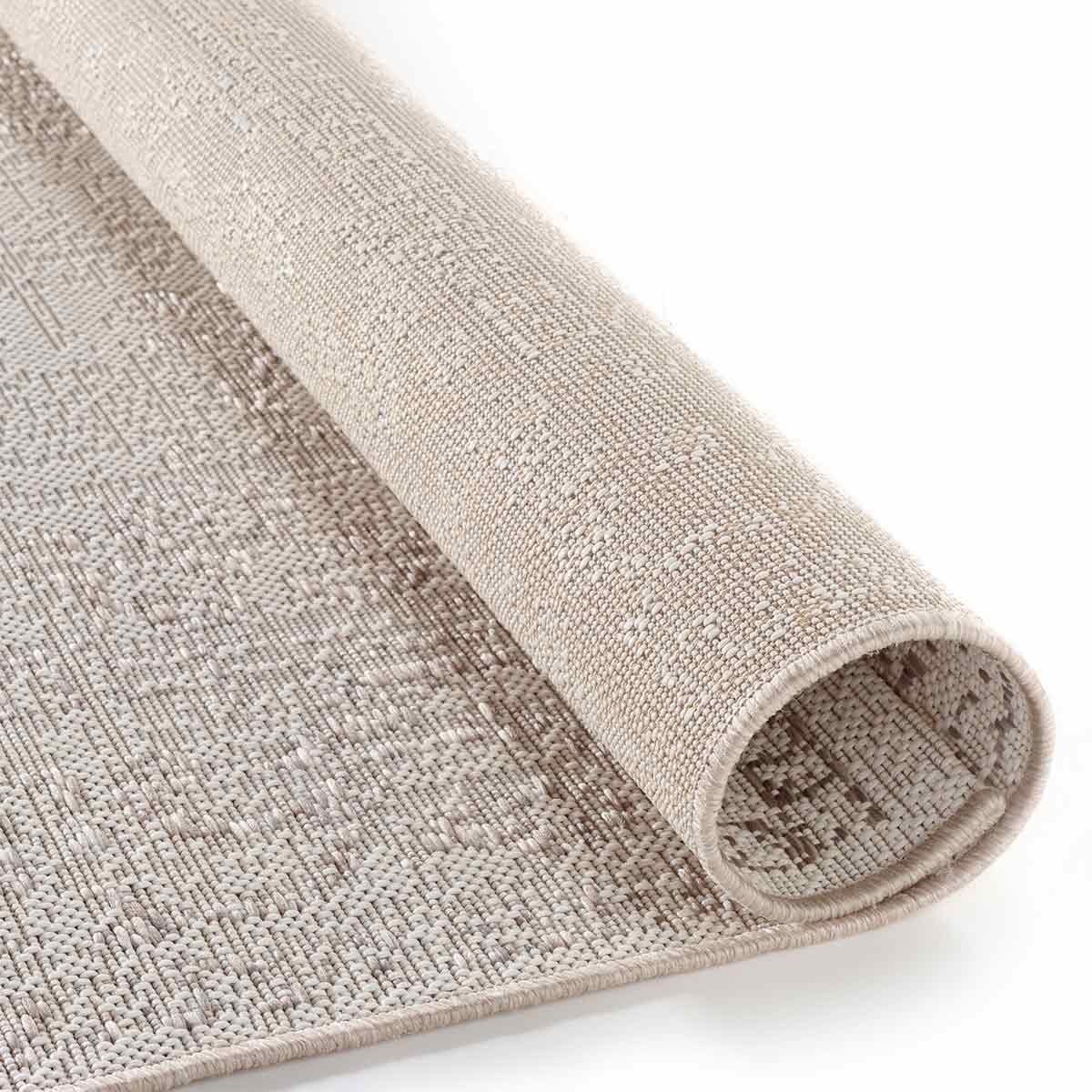 Opgerold beige tapijt met een geweven textuur. Het tapijt is beige met een licht patroon.