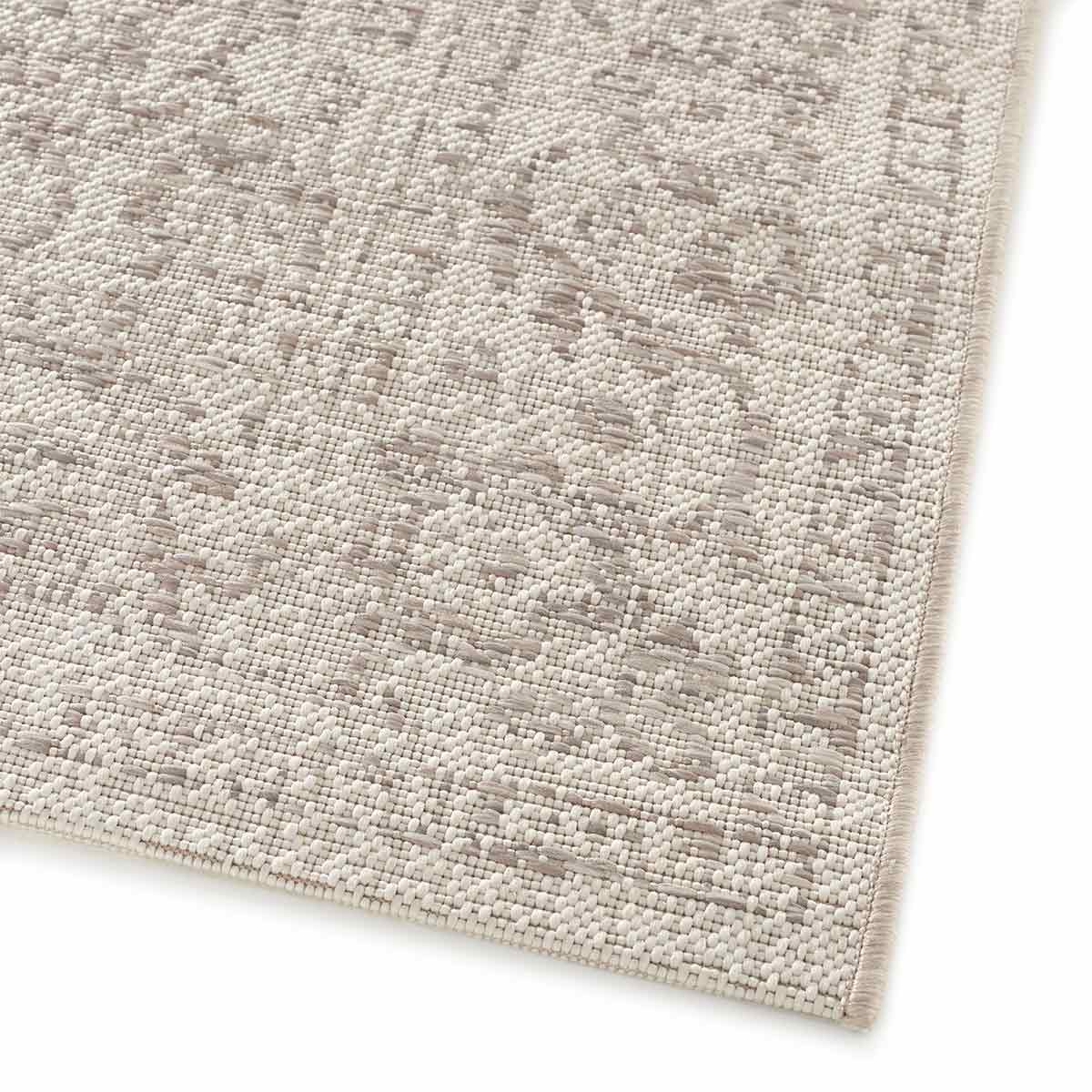Close-up van een witte tapijttextuur. Het tapijt heeft een geweven patroon met beige en witte details.