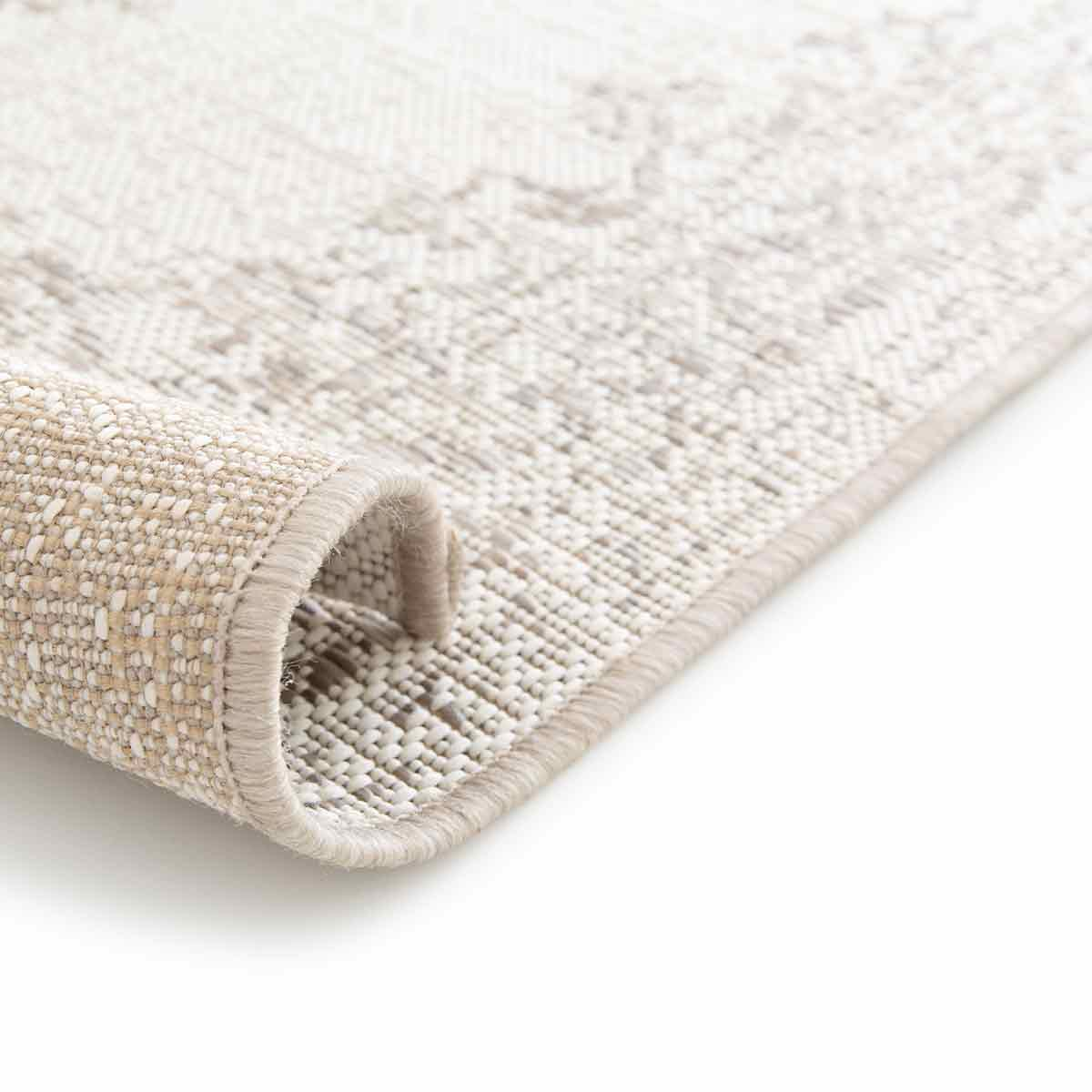 Close-up van opgerold tapijt. Het is beige met een geweven textuur met een lichter patroon.