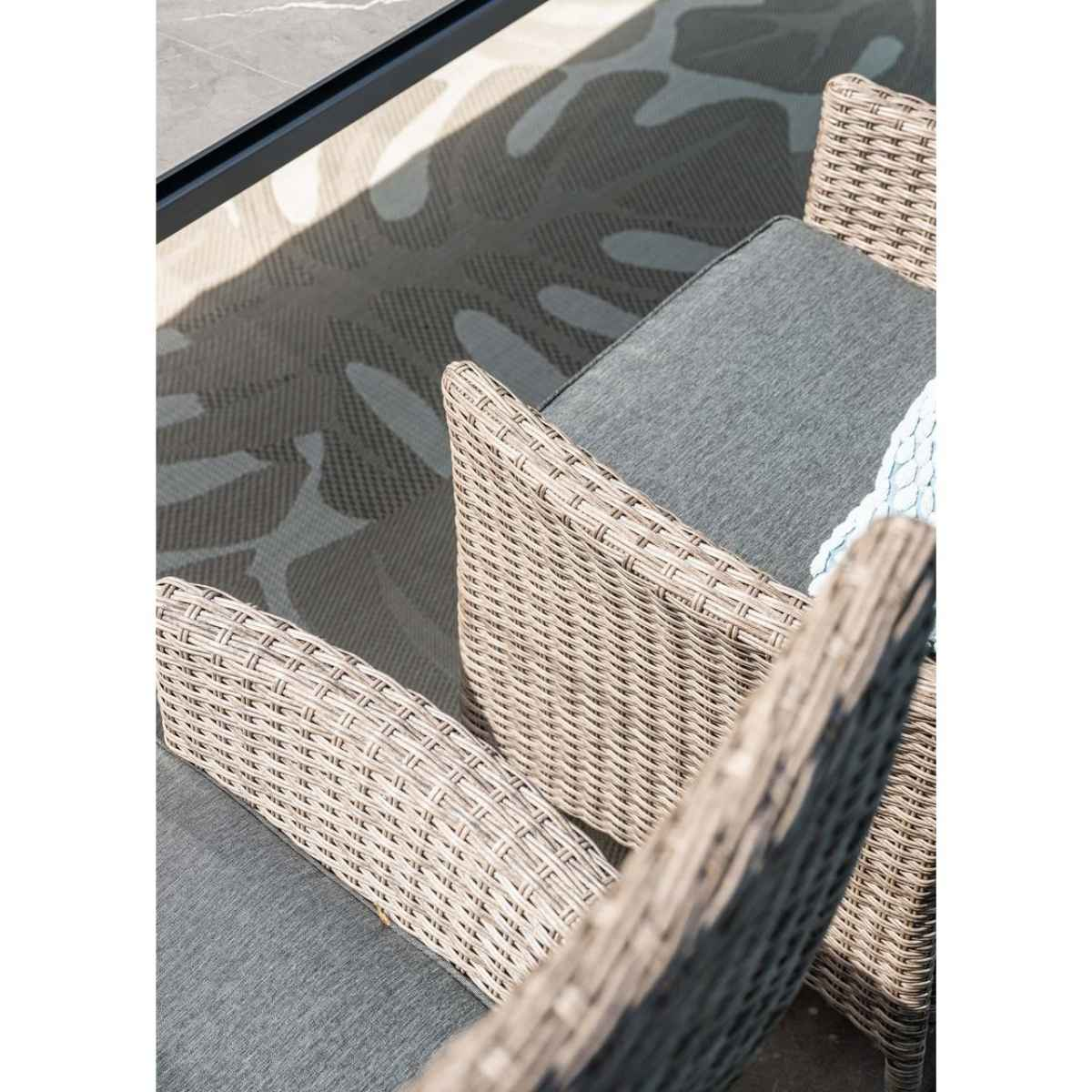 Wicker chairs with gray cushions. The scene shows a high-angle view, and a concrete floor.