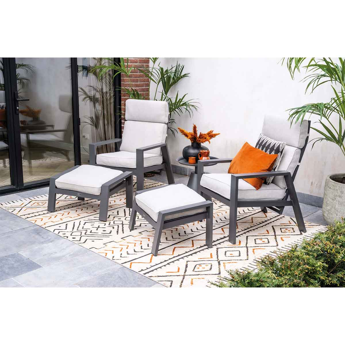 Buiten terras set met stoelen, poefs, tafel en decoratie.