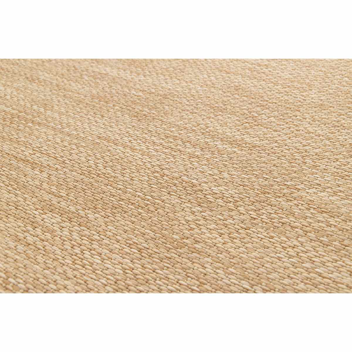 Close-up van een geweven beige vloerkleed met een gestructureerd oppervlak.