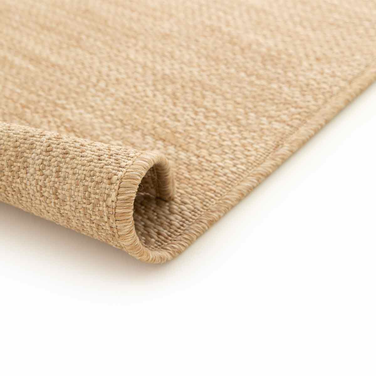 Opgerold beige vloerkleed, met een textuur.