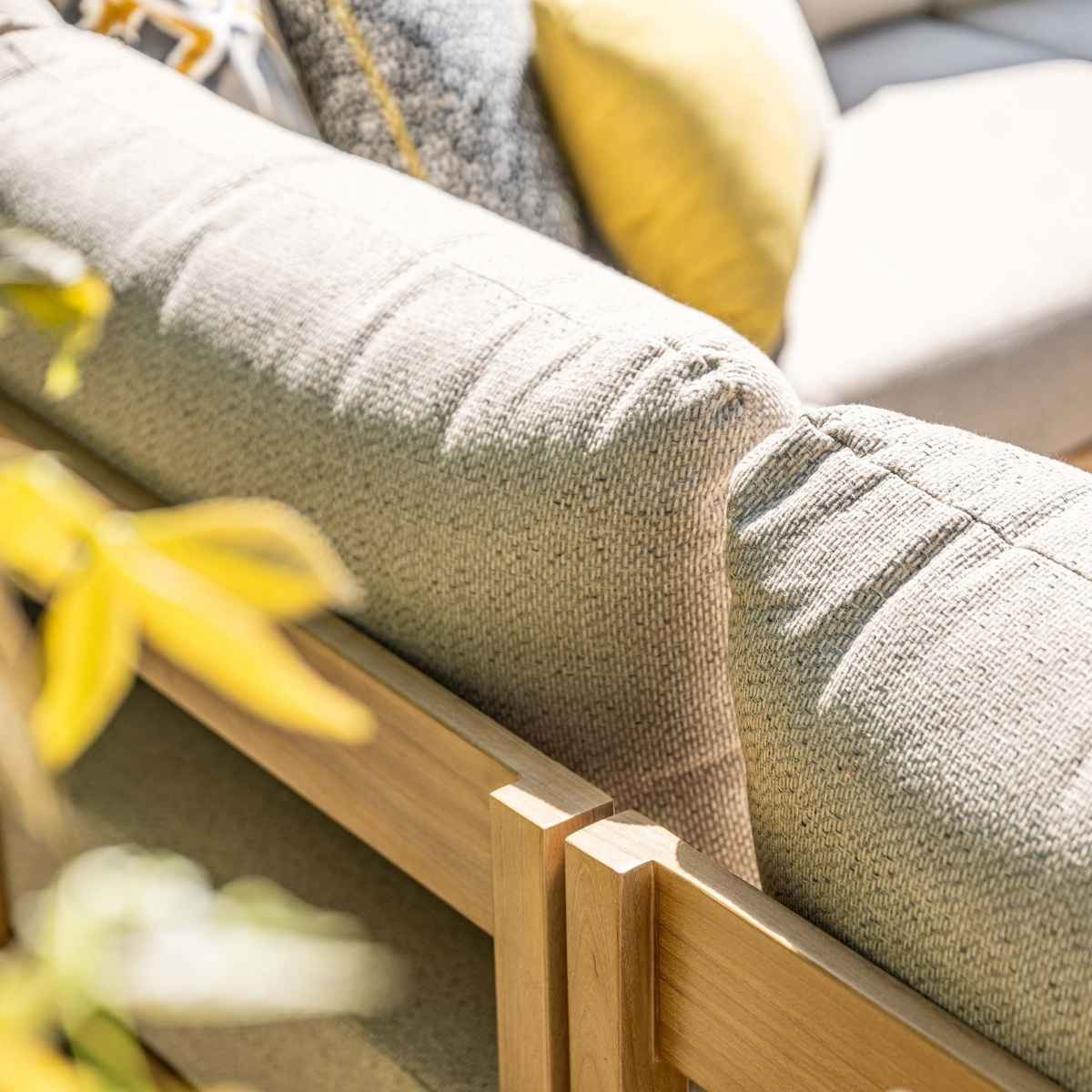 Gros plan sur le coussin de canapé. Tissu vert clair avec cadre en bois et feuilles jaunes en arrière-plan.