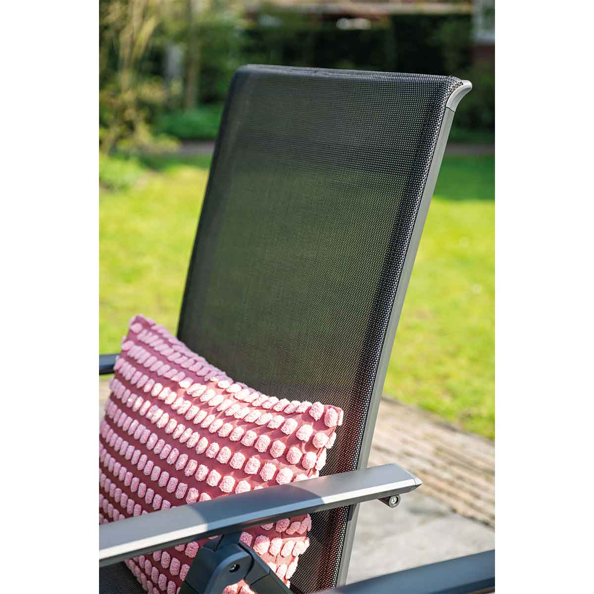 Outdoor chair with a red pillow. Green background.