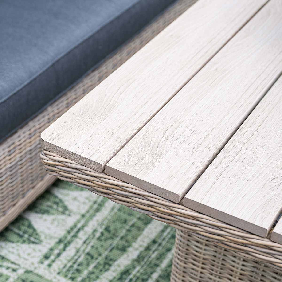 Close-up of light wood table top with woven edges and green rug.