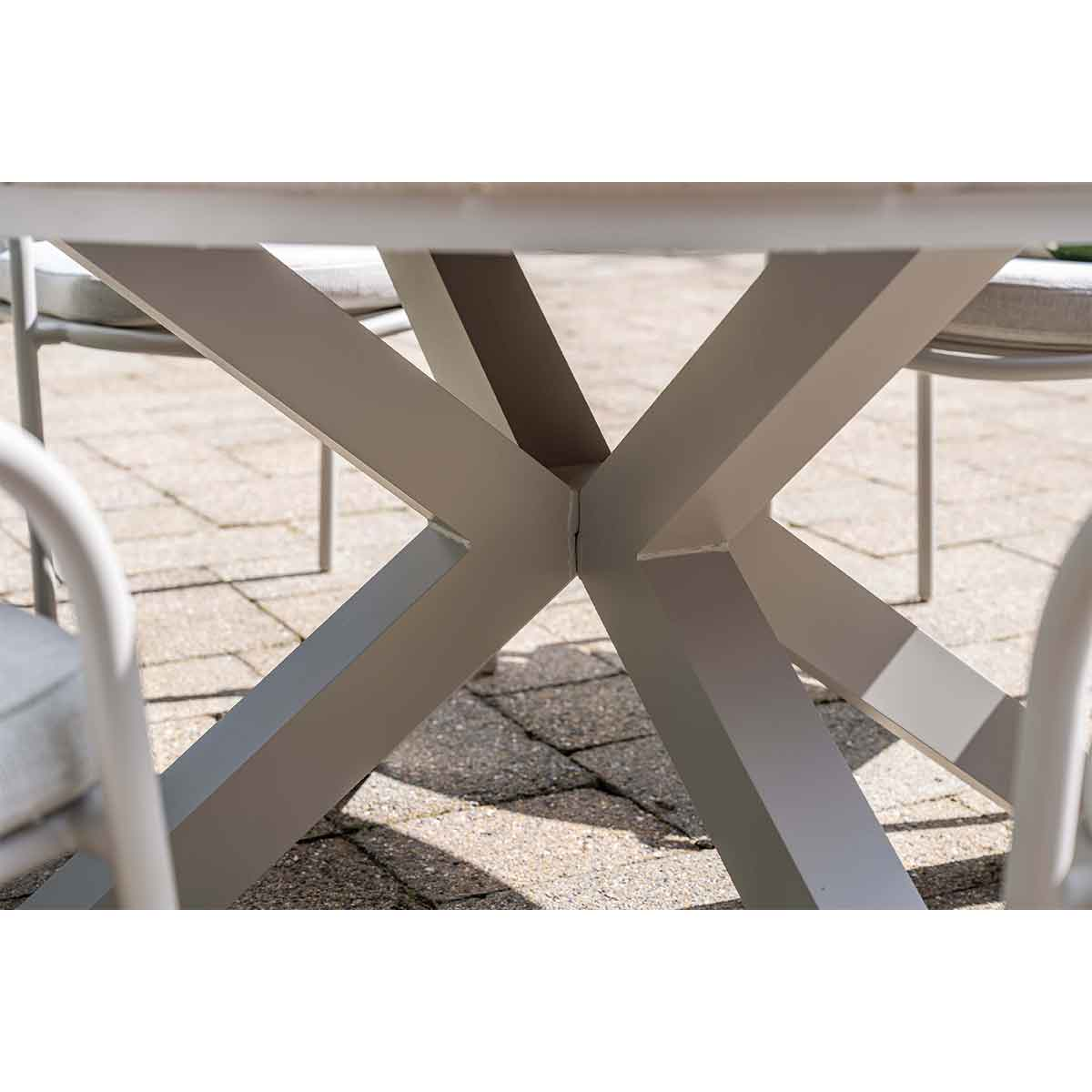 Close-up of a gray metal table base with an X-shaped design and chairs.