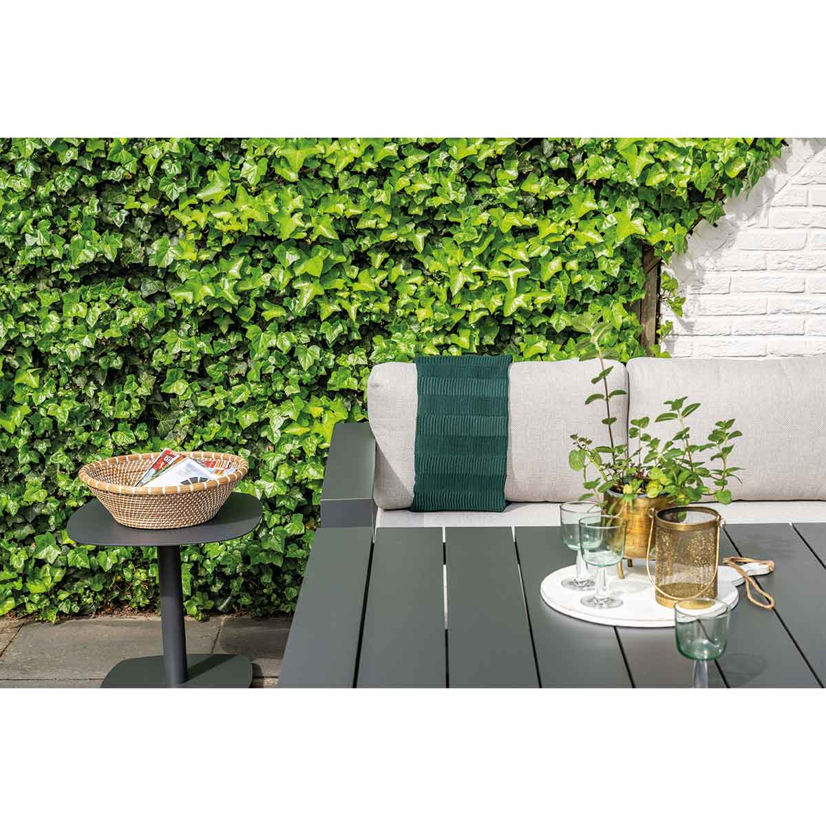 Ensemble de salle à manger extérieur avec table, plantes et panier sur petite table.