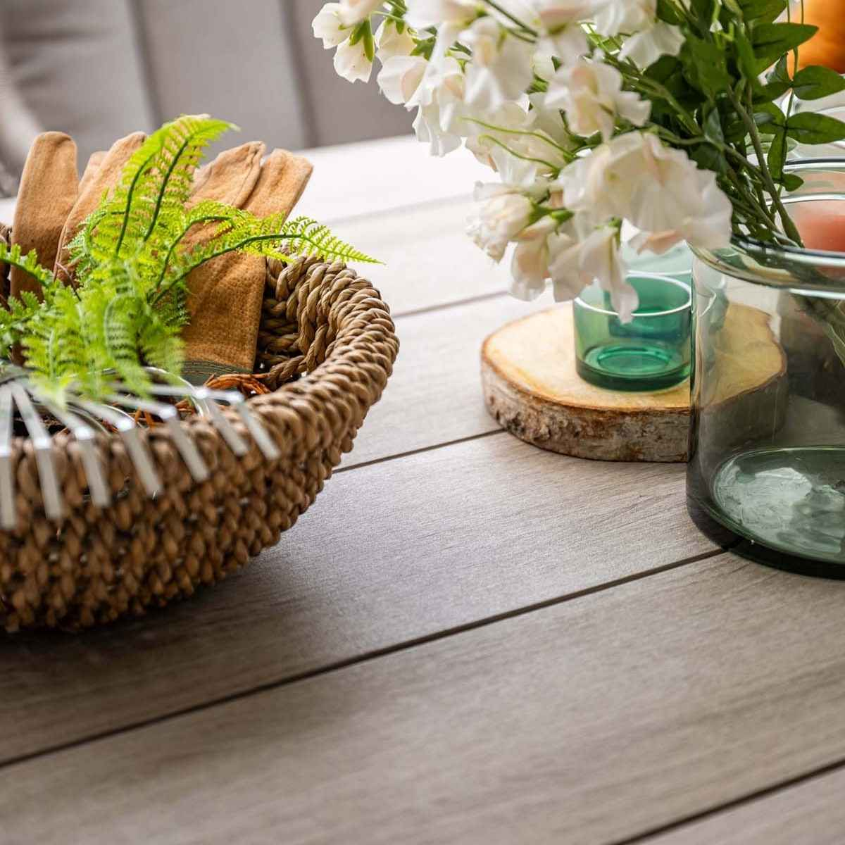 Een tafelsetting met een mand met items, bloemen en glazen potten met groen.
