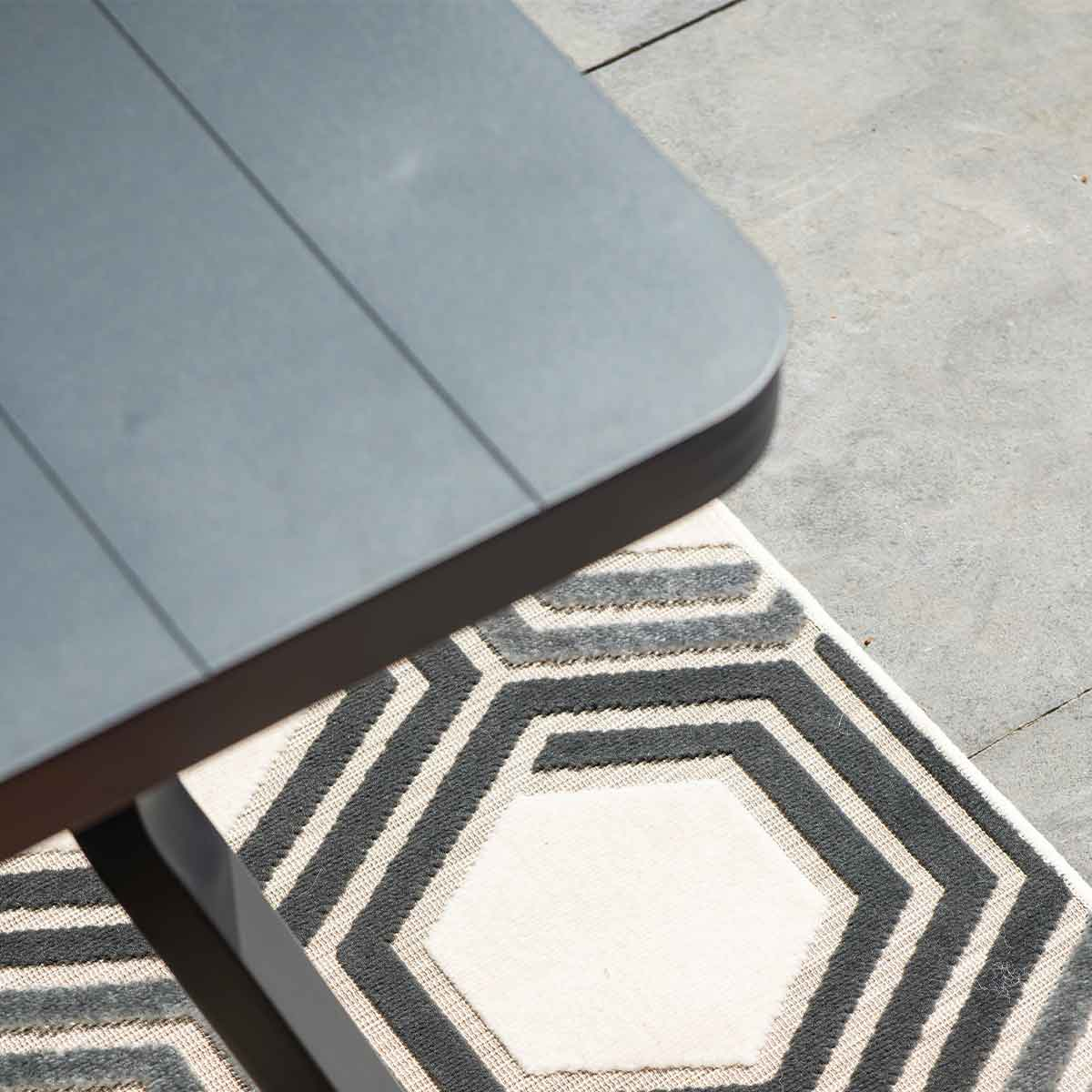 Close-up of a grey table with a geometric patterned rug underneath.