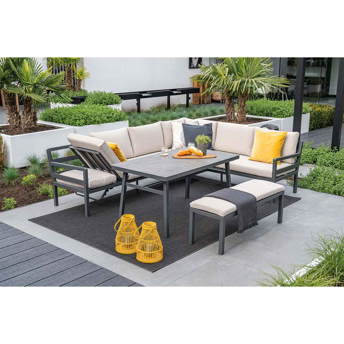 Canapé d'extérieur avec table, banc et lanternes jaunes sur un patio.