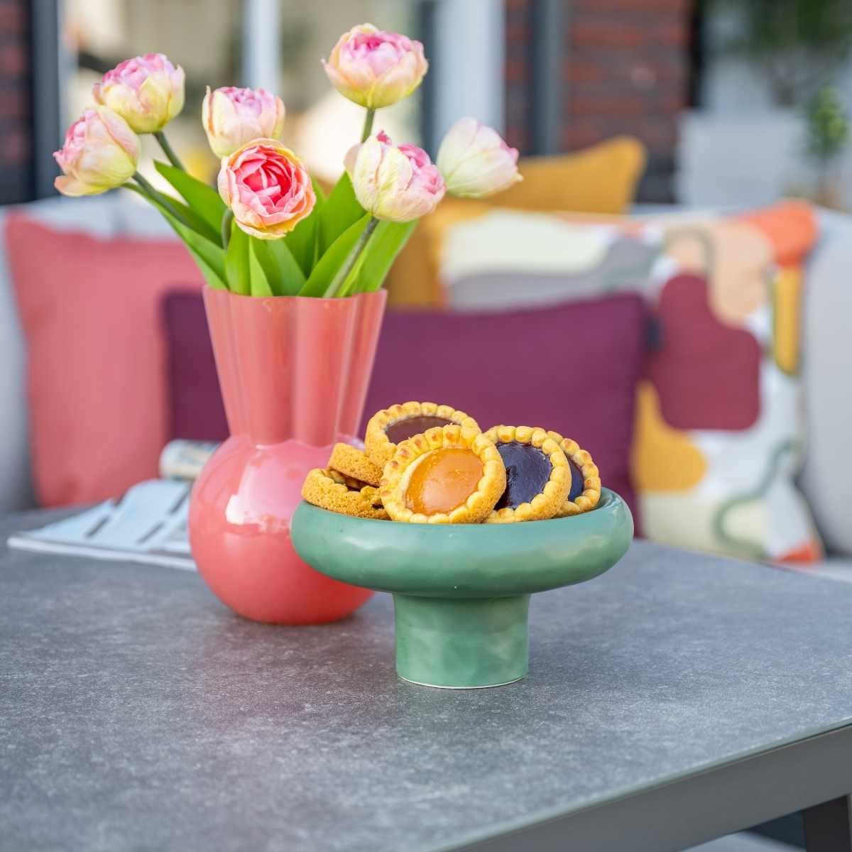 Décoration de table avec fleurs, biscuits et un bol vert.