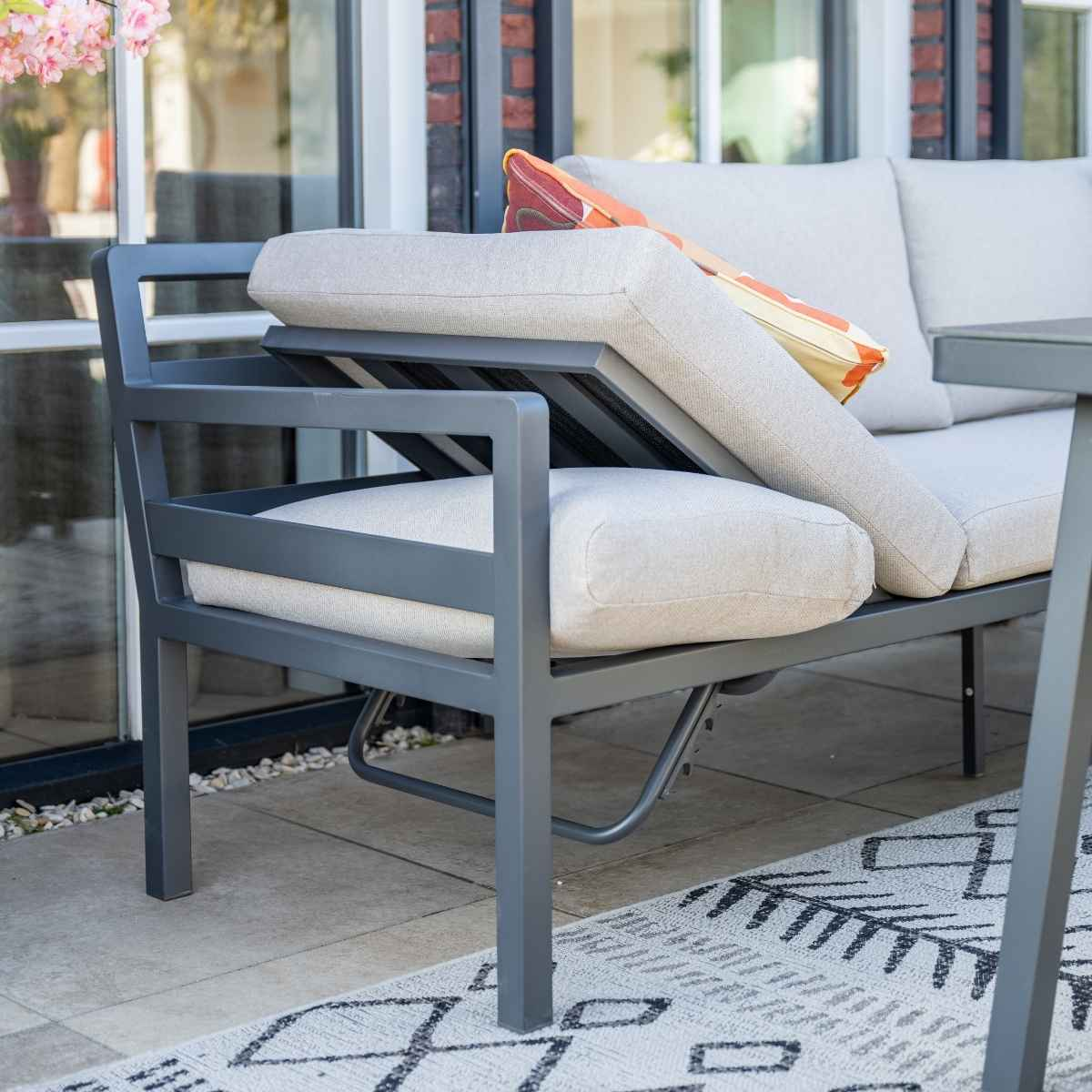 Gros plan sur un canapé d'extérieur avec cadre gris et coussins clairs.