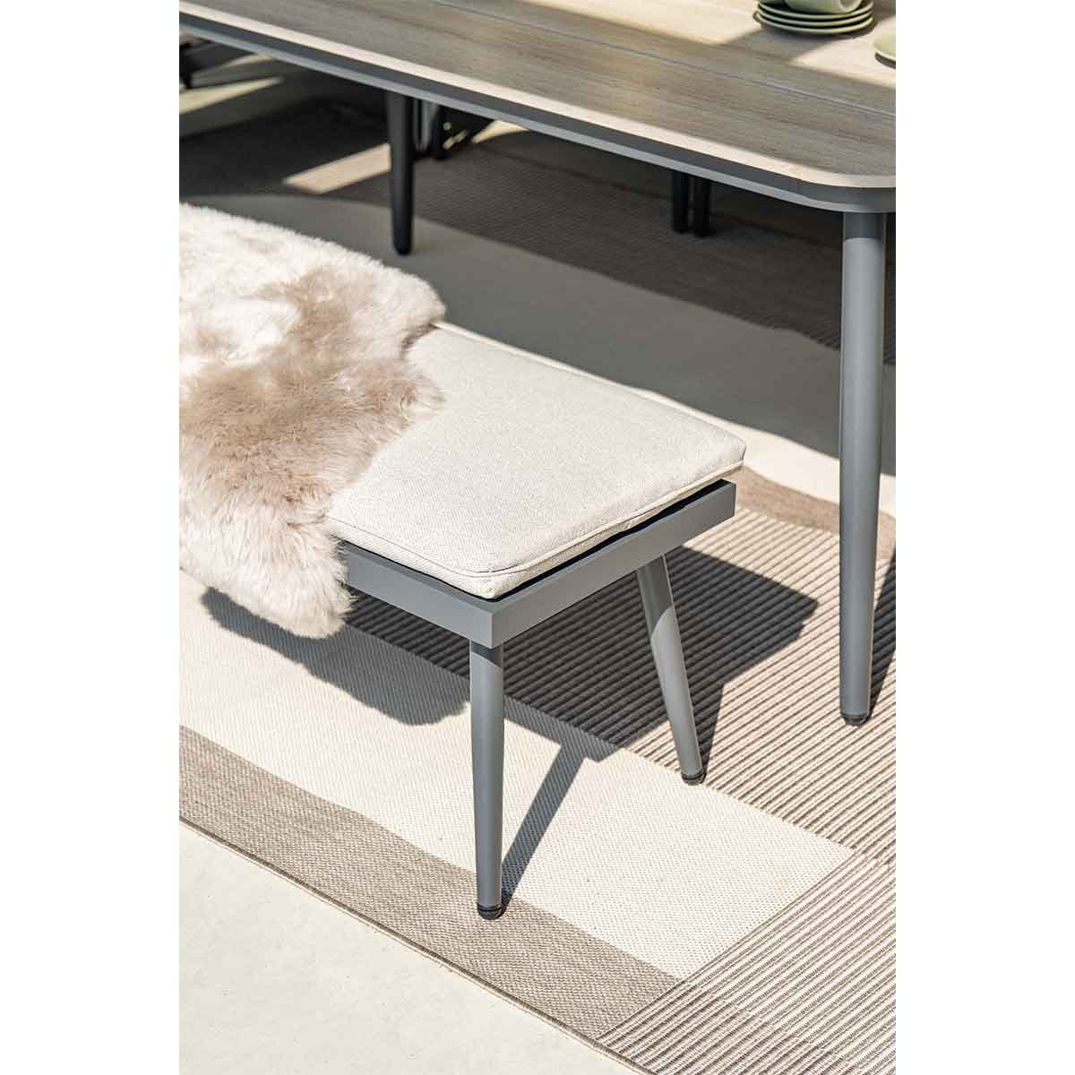 Gros plan sur un banc avec coussin et fausse fourrure sur un tapis.