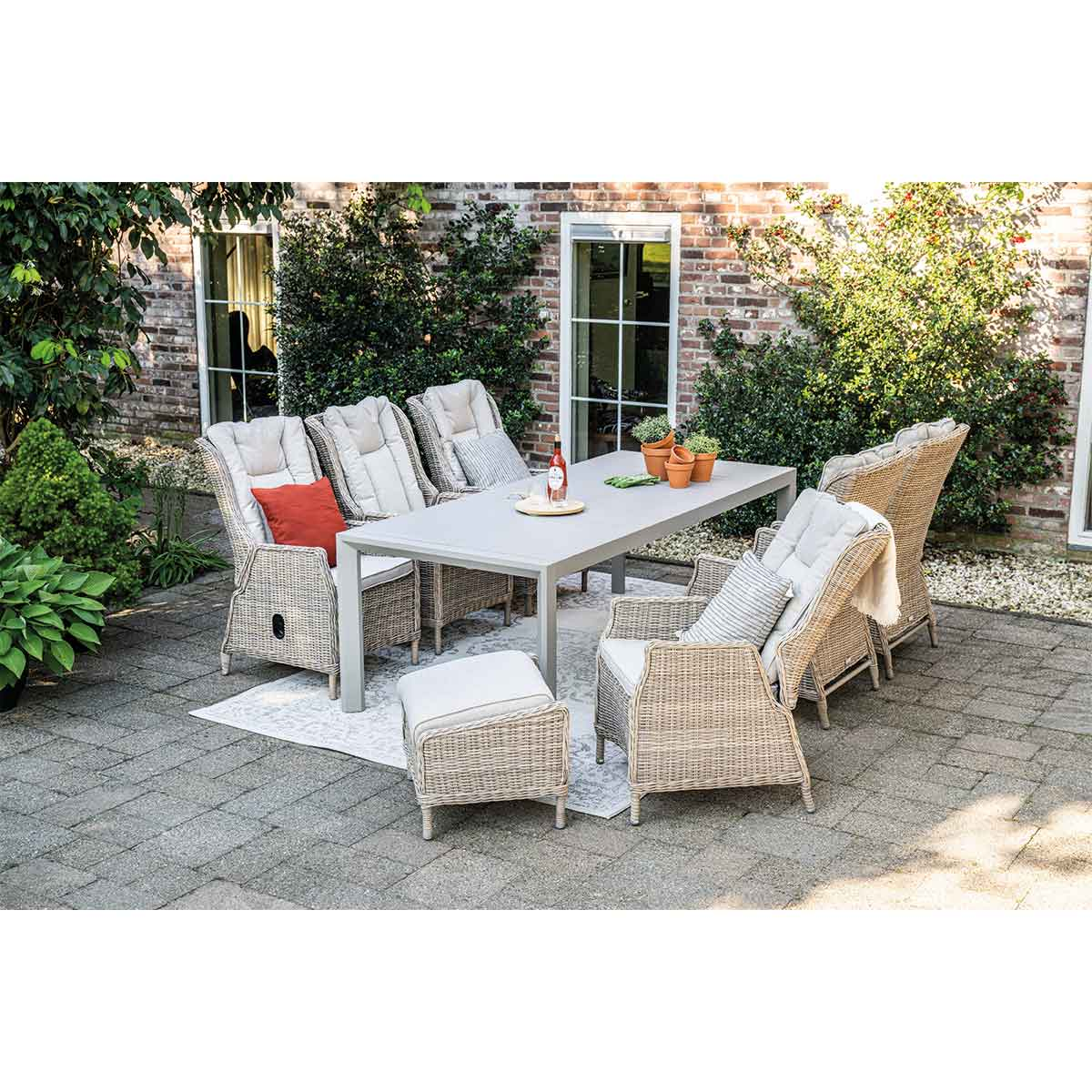 Eethoek buiten met een tafel, stoelen en een bakstenen muur op de achtergrond.