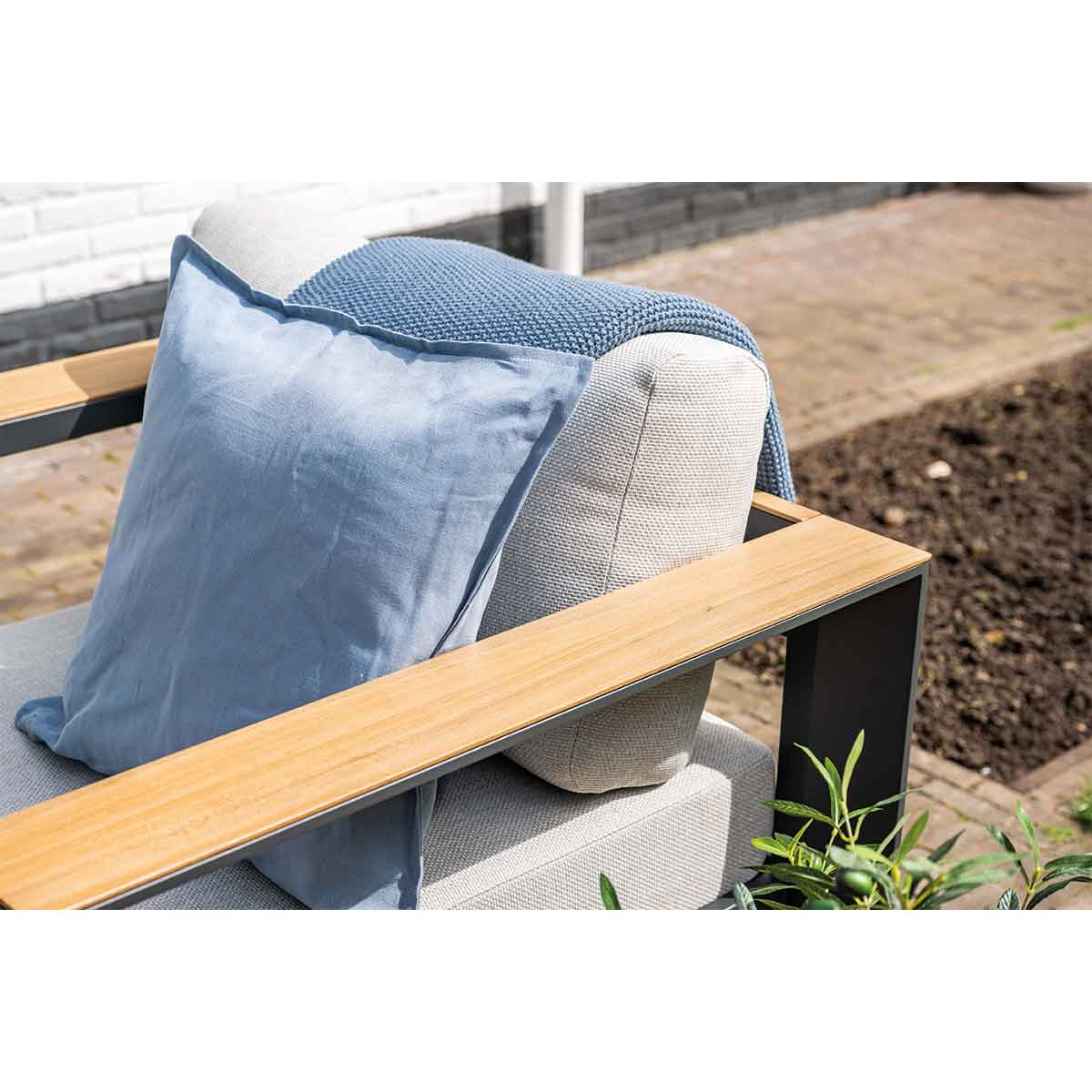 Close-up of a gray outdoor sofa with a blue blanket and pillow.