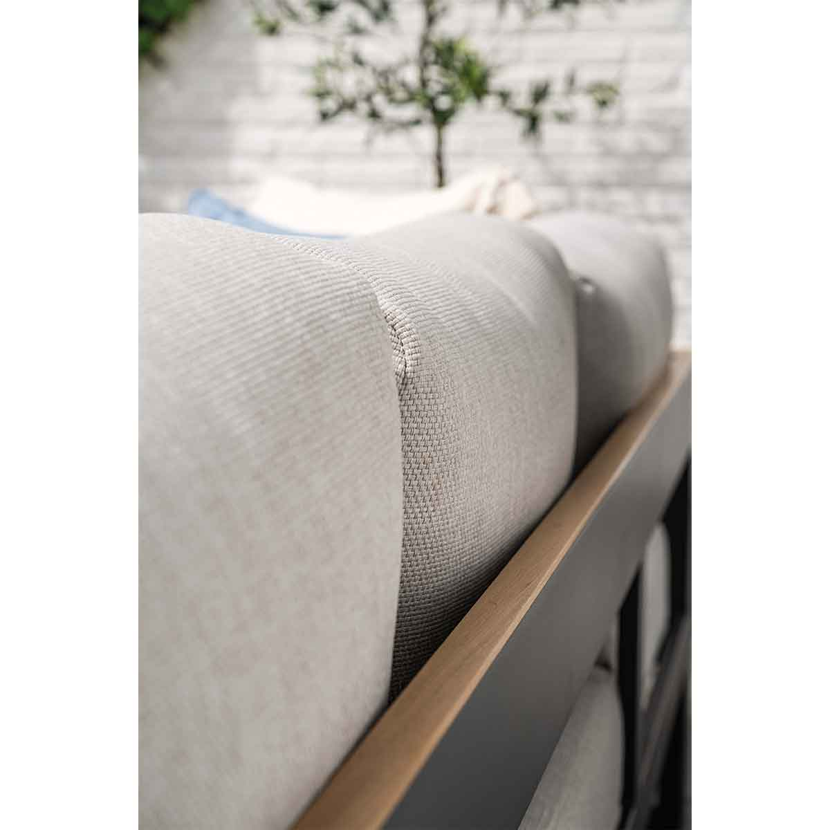 Close-up of a gray sofa with cushions and a wooden armrest.