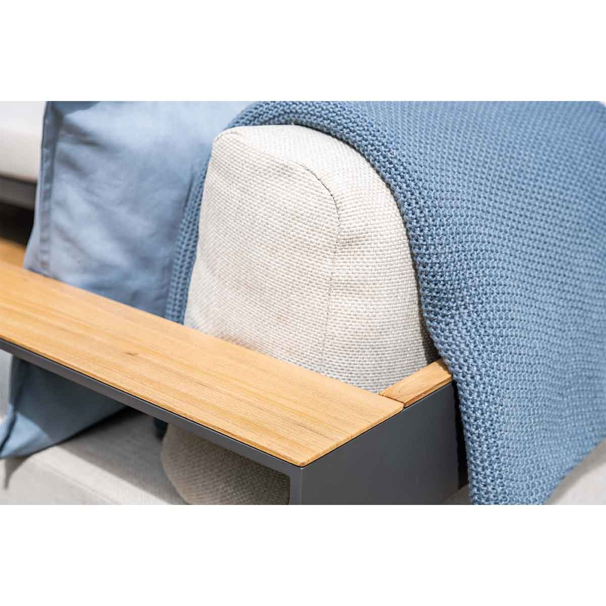 Close-up of a gray sofa with a blue blanket and wooden armrest.