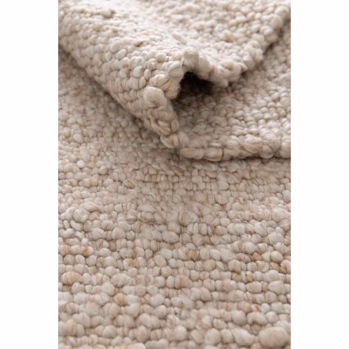 Close-up van beige tapijt. Gerolde rand toont textuur. Grof, noppig, geweven detail.