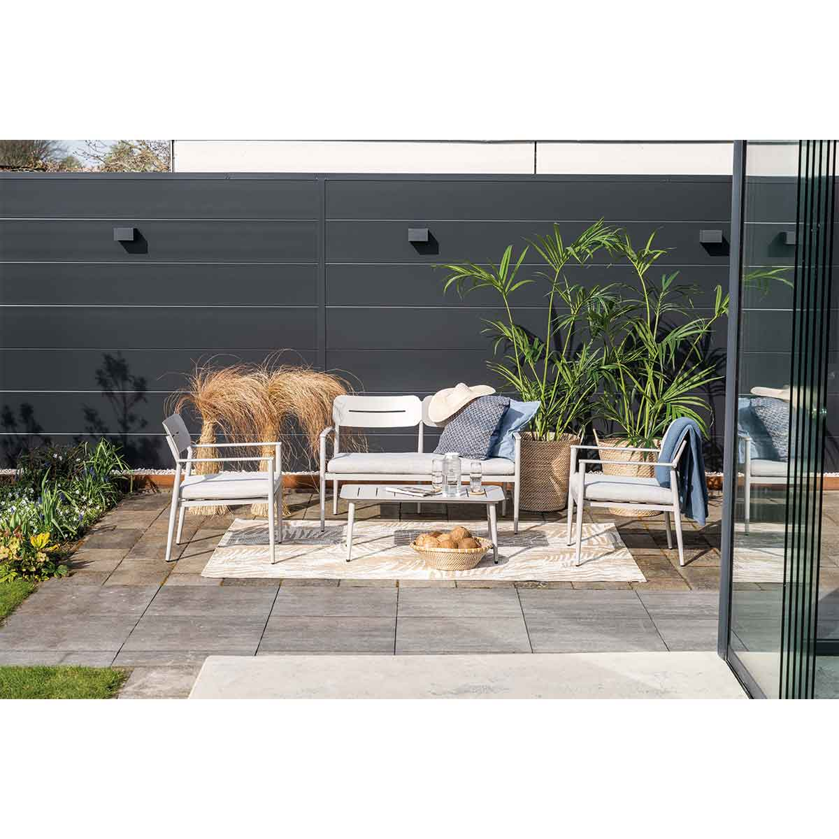 An outdoor seating area with a sofa, two chairs, and a table. The setting is modern and stylish.