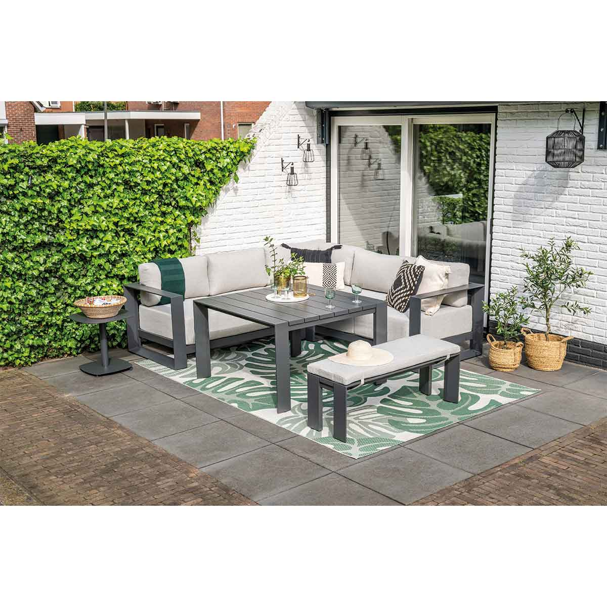 Buitenscène met grijze meubels op een terras. Inclusief bank, tafel, bankje en planten.