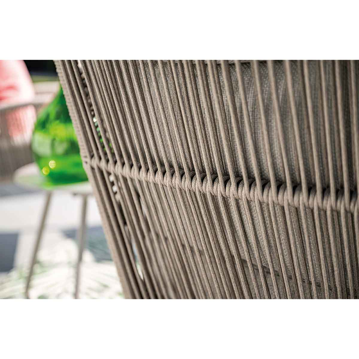 Close up of gray rope detail on a chair. The background is a blurred outdoor scene.