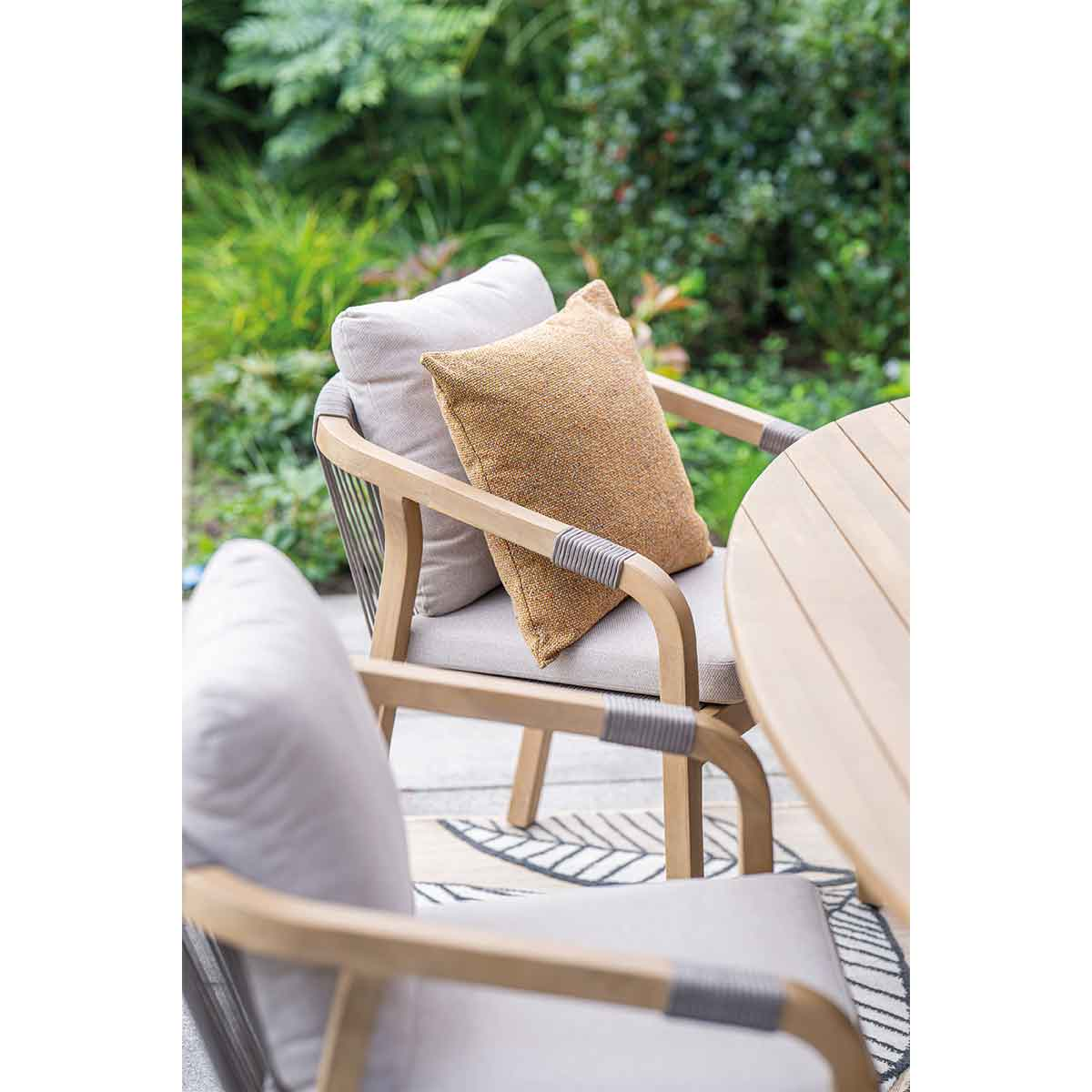 Table setting with chairs, pillows, and a blurred background of a garden.
