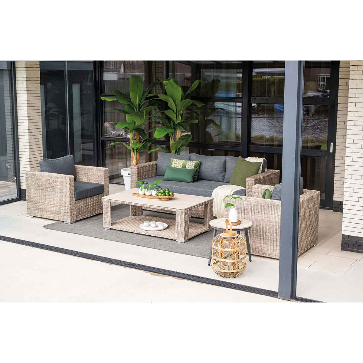 Ensemble de sièges d'extérieur sur le patio. Comprend un canapé, des fauteuils, une table basse, une table d'appoint, des plantes et un tapis.