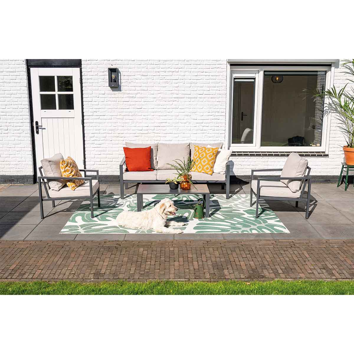 An outdoor scene with outdoor furniture, including a sofa, two chairs, and a table.