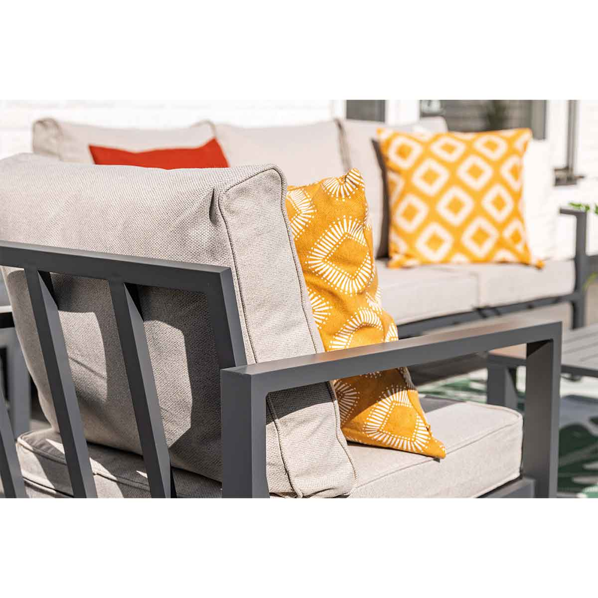 Close up of a gray outdoor chair with yellow and white patterned pillows.