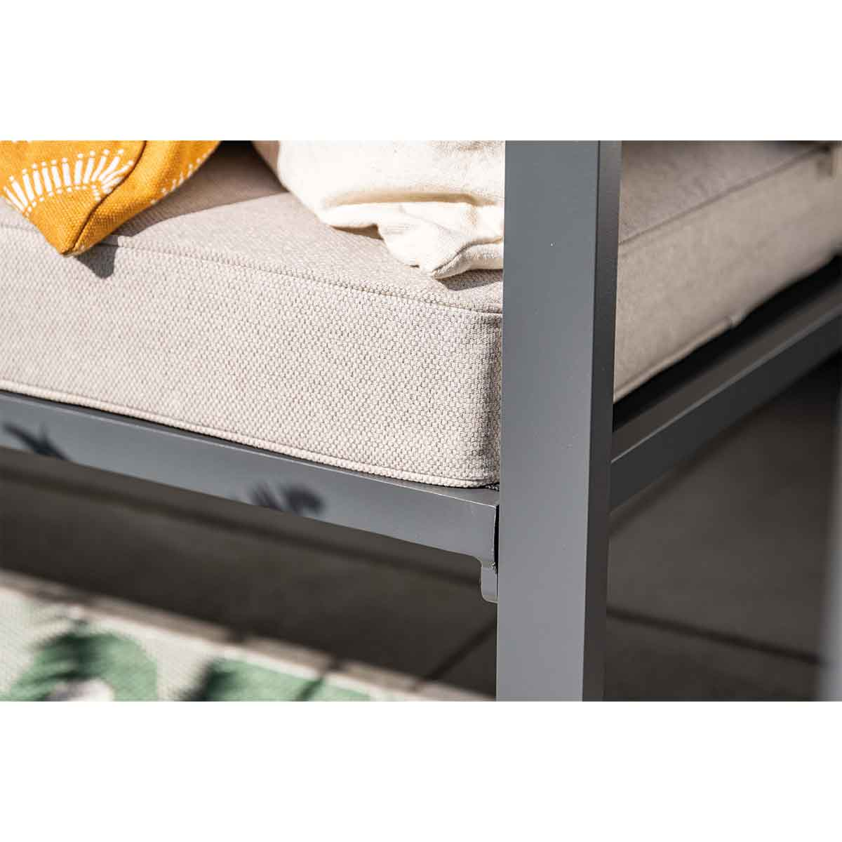Close-up of a gray outdoor chair cushion with a patterned rug in the background.