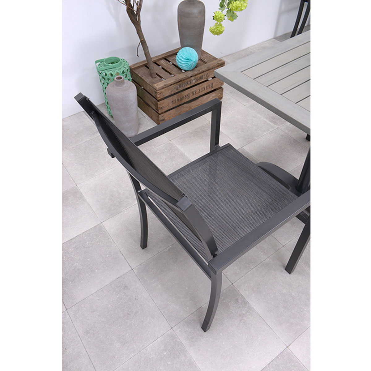 Outdoor dining chair with a dark frame and mesh back, viewed from above.