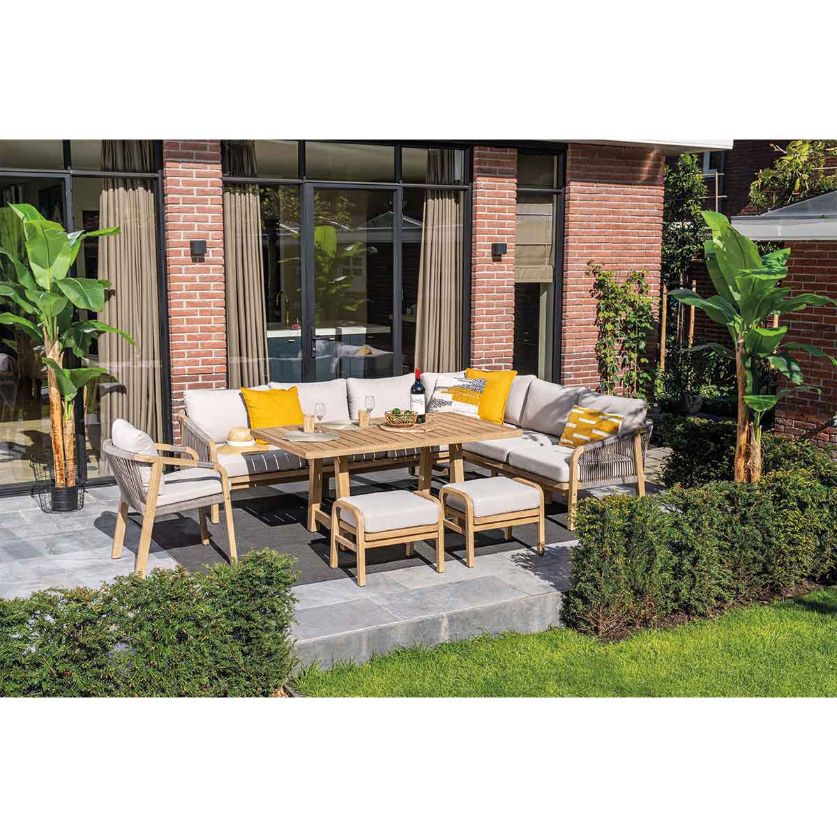 Buiten terras set met tafel, zitplaatsen en planten. Bakstenen gebouw op de achtergrond.
