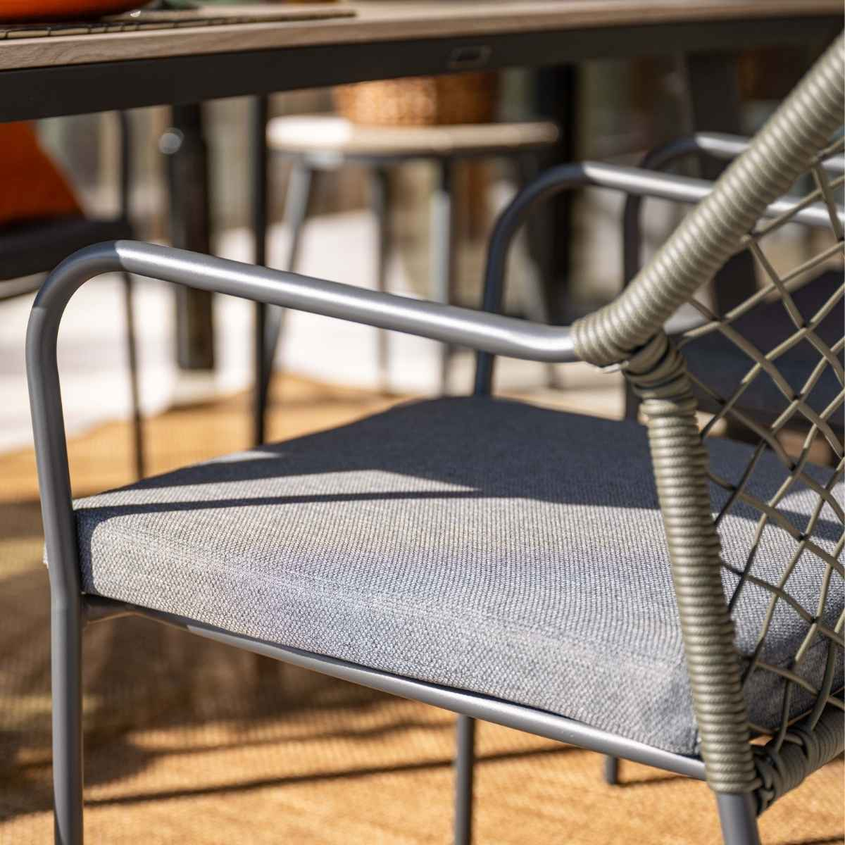 Gros plan d'une chaise avec coussin gris et cadre en corde tressée. Lumière naturelle.